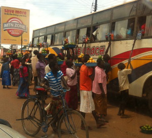 Hawkers crowd a stopped bus. Notice poles to extend wares.